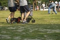 People are pushing the baby carriage and walking on the grassland of a park. Royalty Free Stock Photo