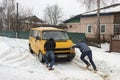 People pushing a car that is stuck in deep snow