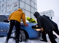 People are pushing out of a snowdrift a car stuck in the snow