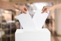 People putting their votes into ballot box, closeup