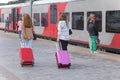 People on the rail station. Two girls with their luggage going to the train on the peron on rail station, back view