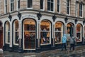 People in raincoats walk past Harvie And Hudson shop on Jermyn Street in St. James, London, UK