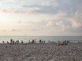 People are relaxing on the beach. People on the seashore meet the sunset