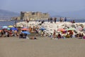 People relaxing on the beach by the Tyrrhenian Sea, colorful umbrellas, Castel dell`Ovo in the background, Naples, Italy