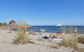 People relaxing on the beach watching a ferry, blue sky and a re Royalty Free Stock Photo