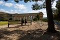 People relaxing on a bench in front of the ancient Doric temple of Segesta Royalty Free Stock Photo