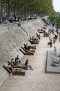 People relaxing on benches on the footpath along the Rhone River