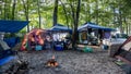 People relaxing in a colorful camp ground around the fire with tents, vans & vehicles in the forest in Ginnie Springs