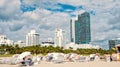 People relaxing on deck chairs under grey umbrellas on beach