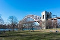 The Hell Gate Bridge over the East River seen from a Field at Astoria Park with People Relaxing