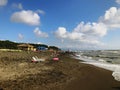 People relaxing by the sea. Splashing waves on a sandy beach. Summer sunny day on the seaside Royalty Free Stock Photo