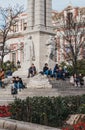 People relaxing on the stairs of the monument on Plaza del Triunfo, Seville, Spain