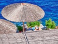 People relaxing under thatched umbrella on blue sea background