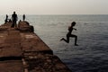 People rest on the pier. Silhouette photo. The fisherman is fishing. The girl jumped into the water.