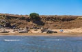 People rest on a wild beach with rocks