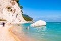People resting on amazing white pebbles beach surrounded by high massive white limestone rocky cliffs meeting Adriatic sea