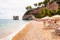 People resting on deckchairs, sunbathing and swimming in Adriatic sea. Famous sea stacks of Baia delle Zagare bay in Gargano
