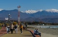 People resting on sunny winter day on Olympic Embankment in Sirius against Caucasus mountains Royalty Free Stock Photo