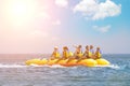 People ride on banana boat. Bright blue sea and blue sky with clouds. Happy vacation. Beach water sport. Hot active summer
