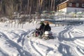 People ride a snowmobile through the village. Winter mode of transport. Off-road riding on a snowmobile. Selective focus