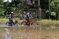 People riding bicycles on the flooded roads