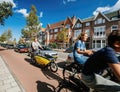 People riding bikes on Haarlem street with woman riding yellow shared Cargoroo e