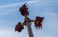 People riding high in the air on a carnival festival ride against blue sky Royalty Free Stock Photo