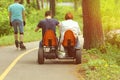 People riding pedal car, back view. New sports and recreation activities in the spring sunlit park.