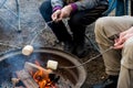 People roasting large marshmallows on a stick over the campfire firepit. Camping family fun Royalty Free Stock Photo