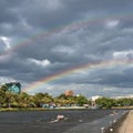 People rowing on Yarra river in Melbourne with rainbow on the ba