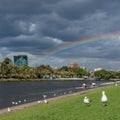 People rowing on Yarra river in Melbourne with rainbow on the ba