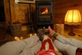 people's feet glowing fireplace, family sitting on floor on white sheepskin, young couple and daughter on Christmas evening Royalty Free Stock Photo