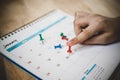 People's hand press red thumbtack on white calendar to marked important date