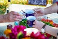 People& x27;s hands with beautiful cups of tea at the outdoor table on a sunny summer day. A joint tea party in the