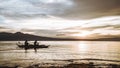 People sailing on a boat in a lake at sunset