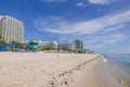 People on sandy Miami beach near tall residential buildings on blue sky with white clouds on background. Royalty Free Stock Photo