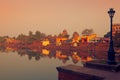 People seat on stone ghats of Bindu Sagar lake and admire beautiful sunset