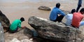 People seating around river bank rocks