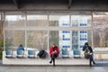 People, senior woman and a young man, and commuters, sitting waiting for a train in Holesovice station and reading books