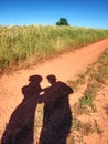 People shadows on old dusty road with ferric red soil. Shadows