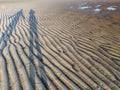 People shadows reflecting in sand ripples at Low Tide with water