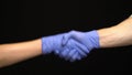 People Shaking Hands in medical gloves on black background