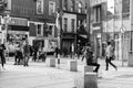 People shopping on Patrick Street in Cork, the main street for stores, street performers, restaurants; photographed in monochrome.