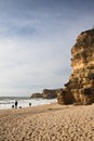 People sightseeing sea caves on wonderful sandy beach with huge cliffs and rocks