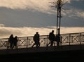 People in the silhouette go over the bridge