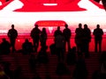 People silhouetted against huge video screen.