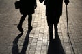 Girl and woman with a cane, black silhouettes and shadows of two people walking on the street Royalty Free Stock Photo