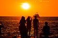 People silhouettes at golden sunset at sea and yacht on horizon Royalty Free Stock Photo