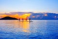 People silhouettes stand SUP paddle boarding, sea sunset beach, active young man woman surfing paddling board, ocean sunrise Royalty Free Stock Photo