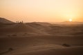 People silhouettes strolling through the dunes of the Sahara desert during sunset Royalty Free Stock Photo